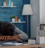A woman with her face down on her desk tired and exhausted.