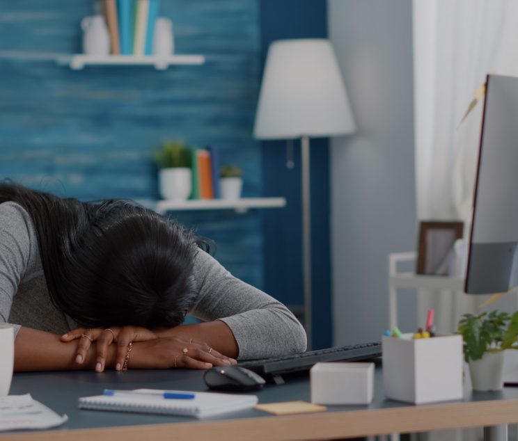 A woman with her face down on her desk tired and exhausted.